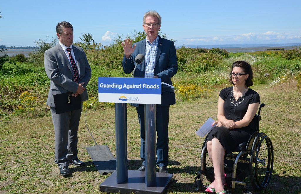 Panorama MLA, Marvin Hunt at the podium presents the dike improvement project details, along with the Hon. Stephanie Cadieux, Cloverdale and Minister of Children and Family Development, and City Councillor Mike Starchuk.