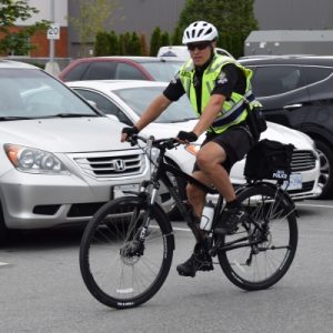 Constable Miller biking through a parking lot.